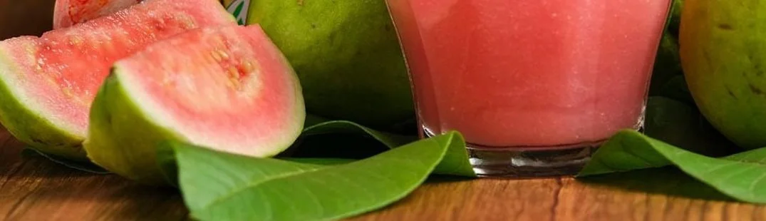 goiaba fatiada, folhas e um copo de suco